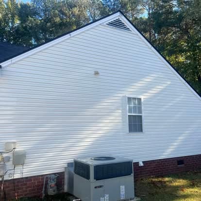 White vinyl siding on a house with a window and an outdoor HVAC unit in a green yard.