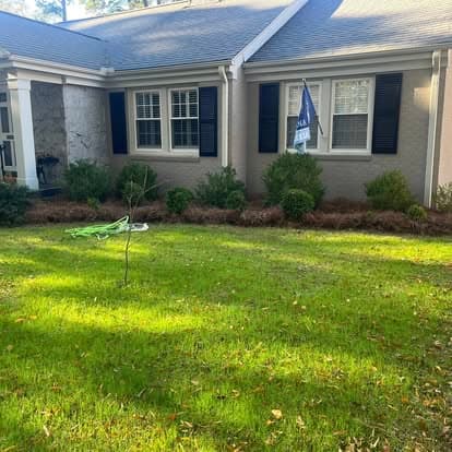 Front yard of a house with manicured lawn, shrubs, and an American flag.